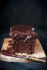 Vista de primer plano de la torta con la extensión de chocolate y cuchillo en el tablero de madera - foto de stock