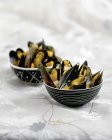 Spicy mussels in small black pots on table — Stock Photo