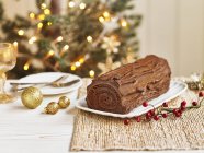 Closeup view of chocolate Yule log with Christmas decorations and berries — Stock Photo