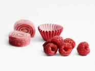 Raspberry rolled candies and paper cups — Stock Photo