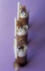 Крупный план шоколадного крема со взбитыми сливками в стаканах с ложками и печеньем в форме звезды — стоковое фото