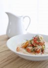 Sopa de cangrejo en plato blanco sobre superficie de madera con jarra - foto de stock