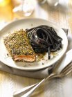 Salmon steak and squid ink pasta — Stock Photo