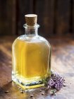 Крупный план домашнего масла в стеклянной бутылке с цветами лаванды — стоковое фото