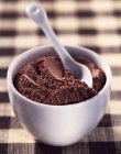 Closeup view of cocoa powder with a ceramic spoon in a bowl — Stock Photo