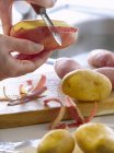 Mains féminines épluchant les pommes de terre — Photo de stock