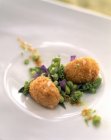 Fried potato balls  with green peas on white plate — Stock Photo