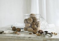 Орехи в стеклянной банке и рядом с ней — стоковое фото