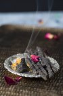 Closeup view of homemade incense sticks and a cone made of charcoal, resin and dried herbs and flowers — Stock Photo