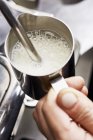 Frothing milk in jug — Stock Photo
