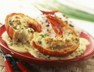 Closeup view of roasted spiny lobster tails with herbs and sauce on plate — Stock Photo