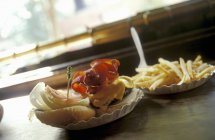 Hamburger and fries on plates — Stock Photo