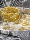 Cocinar pasta linguine en agua hirviendo - foto de stock