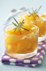 Peaches in jelly with rosemary over towel — Stock Photo