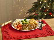 Dado arrosto cena di Natale su piatto bianco sopra asciugamano rosso — Foto stock