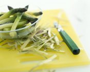 Descascando espargos verdes na placa de corte amarelo — Fotografia de Stock