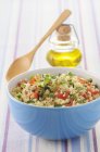 Tabbouleh in blue bowl with woden spoon — Stock Photo