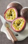 Passion fruit cut in half on white desk with knife — Stock Photo