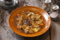 Капустяний суп на коричневій тарілці на дерев'яній поверхні — стокове фото