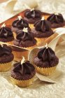 Mini chocolate cupcakes with gold leaves — Stock Photo