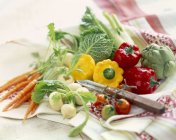 Ассорти карликовых овощей на столе с полотенцем и ножом — стоковое фото