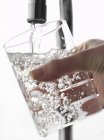 Наполнение стакана воды из крана — стоковое фото