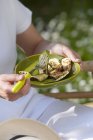 Person eating grilled zucchinis outdoors on plate in hands outdoors , midsection — Stock Photo