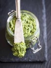 Closeup view of mixed herbal vegan Pesto on a spreader and in a jar — Stock Photo