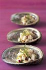 Nahaufnahme von Meeresfrüchte-Gerichten mit Kräutern und Gewürzen in Schalentierklappen auf lila Oberfläche — Stockfoto