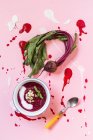 Beet soup in a white bowl on colored construction paper surface - healthy food — Stock Photo