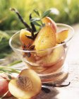 Closeup view of peaches poached in glass bowl with spices — Stock Photo