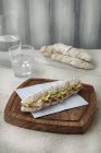 Ein Mini-Baguette mit Mortadella und Salat auf Holztisch — Stockfoto