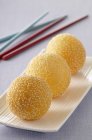 Золотые кунжутные шарики на белой тарелке — стоковое фото