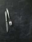 Vista dall'alto di coltello e forchetta su superficie nera — Foto stock