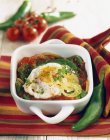 Piperade with fried eggs in  white dish over towel — Stock Photo