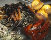 Closeup view of assorted shellfish with burning candles — Stock Photo