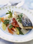Grilled piece of bass with granulated salt and young vegetables  on white plate — Stock Photo