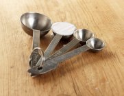 Closeup view of four measuring spoons with baking powder on a wooden surface — Stock Photo