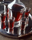 Closeup view of blackcurrant liqueur in glasses and bottle on tray — Stock Photo