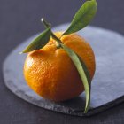 Mandarino con foglie su vassoio di pietra — Foto stock
