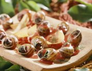 Улитки в остром соусе, филейные чипсы на деревянном столе — стоковое фото