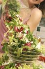 Frau streut gemischten Salat — Stockfoto