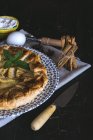 Vue rapprochée de tarte aux pommes sur une assiette avec cannelle, oeufs et sucre glace sur le fond — Photo de stock