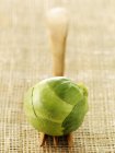 Brussels sprout on wooden fork over textile surface — Stock Photo
