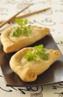 Chinese turnovers on small black plate — Stock Photo