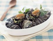 Mussels stuufed with harbs on white plate over towel — Stock Photo