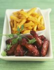 Closeup view of chicken drumsticks with French fries — Stock Photo