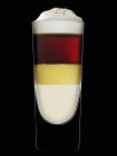 Nahaufnahme von geschichtetem Drink mit Eierlikör vor schwarzem Hintergrund — Stockfoto