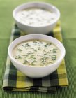 Vichyssoise in white bowls over towel on green surface — Stock Photo