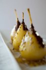 Sweet pears with chocolate and fennel seeds on white textile surface — Stock Photo